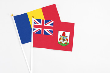 Fototapeta premium Bermuda and Romania stick flags on white background. High quality fabric, miniature national flag. Peaceful global concept.White floor for copy space.