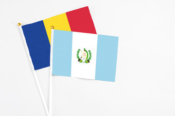 Guatemala and Romania stick flags on white background. High quality fabric, miniature national flag. Peaceful global concept.White floor for copy space.