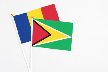 Guyana and Romania stick flags on white background. High quality fabric, miniature national flag. Peaceful global concept.White floor for copy space.