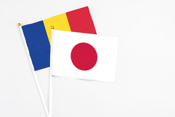 Japan and Romania stick flags on white background. High quality fabric, miniature national flag. Peaceful global concept.White floor for copy space.