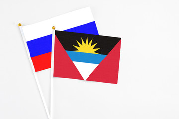 Antigua and Barbuda and Russia stick flags on white background. High quality fabric, miniature national flag. Peaceful global concept.White floor for copy space.