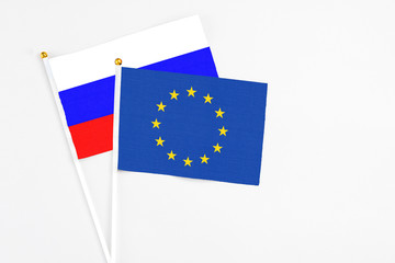 European Union and Russia stick flags on white background. High quality fabric, miniature national flag. Peaceful global concept.White floor for copy space.