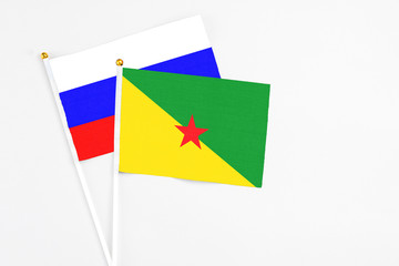 French Guiana and Russia stick flags on white background. High quality fabric, miniature national flag. Peaceful global concept.White floor for copy space.