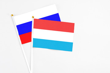 Luxembourg and Russia stick flags on white background. High quality fabric, miniature national flag. Peaceful global concept.White floor for copy space.