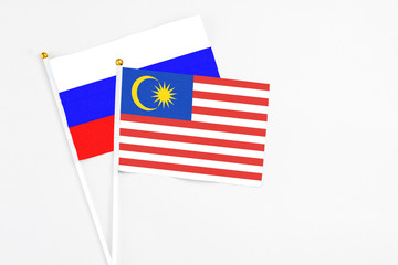 Malaysia and Russia stick flags on white background. High quality fabric, miniature national flag. Peaceful global concept.White floor for copy space.