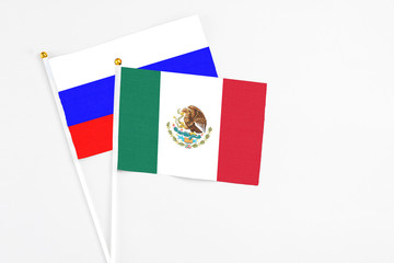 Mexico and Russia stick flags on white background. High quality fabric, miniature national flag. Peaceful global concept.White floor for copy space.
