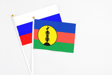 New Caledonia and Russia stick flags on white background. High quality fabric, miniature national flag. Peaceful global concept.White floor for copy space.