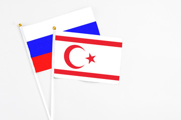 Northern Cyprus and Russia stick flags on white background. High quality fabric, miniature national flag. Peaceful global concept.White floor for copy space.