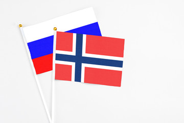 Norway and Russia stick flags on white background. High quality fabric, miniature national flag. Peaceful global concept.White floor for copy space.