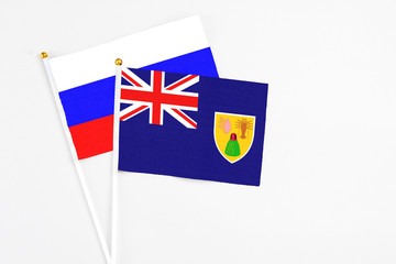 Fototapeta premium Turks And Caicos Islands and Russia stick flags on white background. High quality fabric, miniature national flag. Peaceful global concept.White floor for copy space.