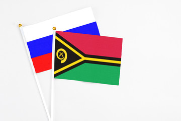 Vanuatu and Russia stick flags on white background. High quality fabric, miniature national flag. Peaceful global concept.White floor for copy space.
