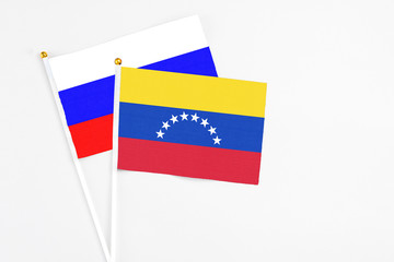 Venezuela and Russia stick flags on white background. High quality fabric, miniature national flag. Peaceful global concept.White floor for copy space.