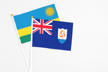 Fototapeta premium Anguilla and Rwanda stick flags on white background. High quality fabric, miniature national flag. Peaceful global concept.White floor for copy space.