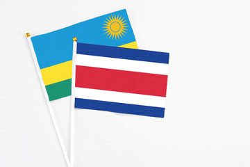 Costa Rica and Rwanda stick flags on white background. High quality fabric, miniature national flag. Peaceful global concept.White floor for copy space.