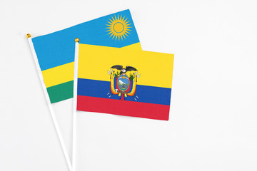 Ecuador and Rwanda stick flags on white background. High quality fabric, miniature national flag. Peaceful global concept.White floor for copy space.