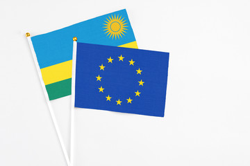 European Union and Rwanda stick flags on white background. High quality fabric, miniature national flag. Peaceful global concept.White floor for copy space.