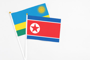 North Korea and Rwanda stick flags on white background. High quality fabric, miniature national flag. Peaceful global concept.White floor for copy space.