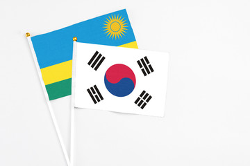 South Korea and Rwanda stick flags on white background. High quality fabric, miniature national flag. Peaceful global concept.White floor for copy space.