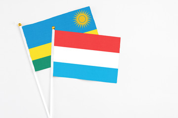 Luxembourg and Rwanda stick flags on white background. High quality fabric, miniature national flag. Peaceful global concept.White floor for copy space.