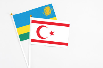 Northern Cyprus and Rwanda stick flags on white background. High quality fabric, miniature national flag. Peaceful global concept.White floor for copy space.