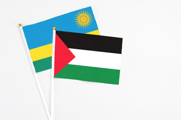 Palestine and Rwanda stick flags on white background. High quality fabric, miniature national flag. Peaceful global concept.White floor for copy space.