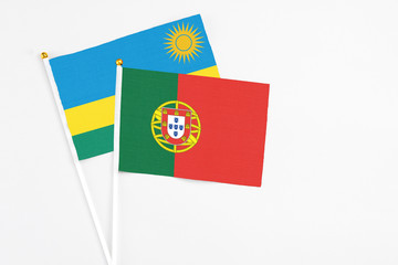 Portugal and Rwanda stick flags on white background. High quality fabric, miniature national flag. Peaceful global concept.White floor for copy space.