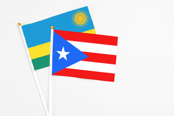 Fototapeta premium Puerto Rico and Rwanda stick flags on white background. High quality fabric, miniature national flag. Peaceful global concept.White floor for copy space.