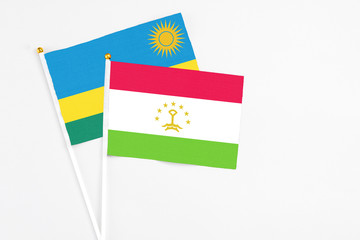 Tajikistan and Rwanda stick flags on white background. High quality fabric, miniature national flag. Peaceful global concept.White floor for copy space.