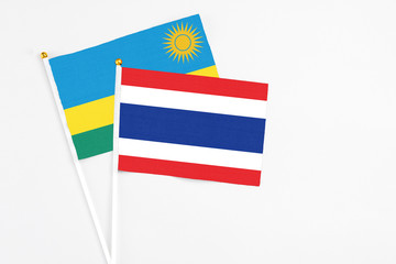 Thailand and Rwanda stick flags on white background. High quality fabric, miniature national flag. Peaceful global concept.White floor for copy space.