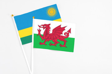 Wales and Rwanda stick flags on white background. High quality fabric, miniature national flag. Peaceful global concept.White floor for copy space.