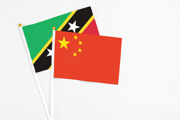 China and Saint Kitts And Nevis stick flags on white background. High quality fabric, miniature national flag. Peaceful global concept.White floor for copy space.