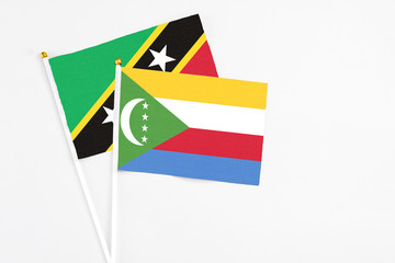 Comoros and Saint Kitts And Nevis stick flags on white background. High quality fabric, miniature national flag. Peaceful global concept.White floor for copy space.