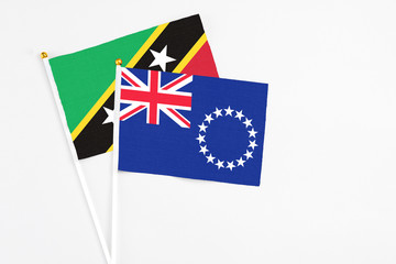 Fototapeta premium Cook Islands and Saint Kitts And Nevis stick flags on white background. High quality fabric, miniature national flag. Peaceful global concept.White floor for copy space.