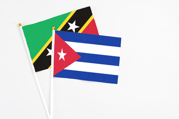 Cuba and Saint Kitts And Nevis stick flags on white background. High quality fabric, miniature national flag. Peaceful global concept.White floor for copy space.