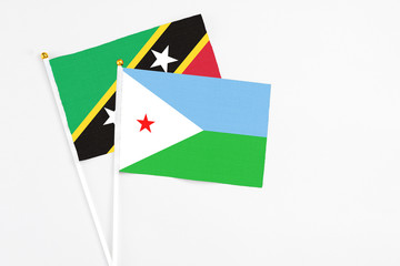 Djibouti and Saint Kitts And Nevis stick flags on white background. High quality fabric, miniature national flag. Peaceful global concept.White floor for copy space.