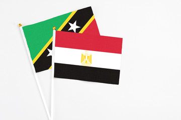 Egypt and Saint Kitts And Nevis stick flags on white background. High quality fabric, miniature national flag. Peaceful global concept.White floor for copy space.