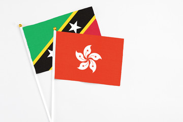 Hong Kong and Saint Kitts And Nevis stick flags on white background. High quality fabric, miniature national flag. Peaceful global concept.White floor for copy space.