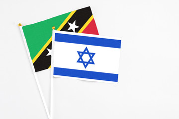 Israel and Saint Kitts And Nevis stick flags on white background. High quality fabric, miniature national flag. Peaceful global concept.White floor for copy space.
