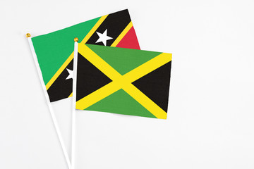 Jamaica and Saint Kitts And Nevis stick flags on white background. High quality fabric, miniature national flag. Peaceful global concept.White floor for copy space.