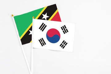 South Korea and Saint Kitts And Nevis stick flags on white background. High quality fabric, miniature national flag. Peaceful global concept.White floor for copy space.