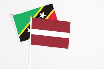 Latvia and Saint Kitts And Nevis stick flags on white background. High quality fabric, miniature national flag. Peaceful global concept.White floor for copy space.