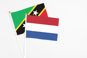 Netherlands and Saint Kitts And Nevis stick flags on white background. High quality fabric, miniature national flag. Peaceful global concept.White floor for copy space.