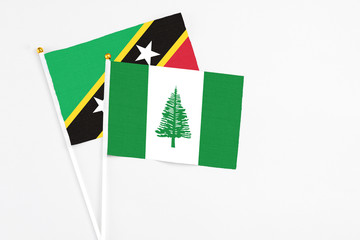 Norfolk Island and Saint Kitts And Nevis stick flags on white background. High quality fabric, miniature national flag. Peaceful global concept.White floor for copy space.