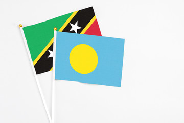 Palau and Saint Kitts And Nevis stick flags on white background. High quality fabric, miniature national flag. Peaceful global concept.White floor for copy space.