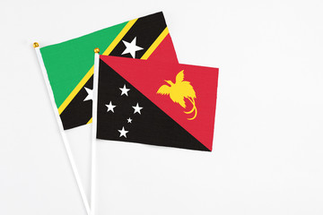 Papua New Guinea and Saint Kitts And Nevis stick flags on white background. High quality fabric, miniature national flag. Peaceful global concept.White floor for copy space.