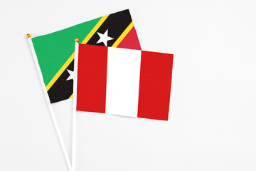 Peru and Saint Kitts And Nevis stick flags on white background. High quality fabric, miniature national flag. Peaceful global concept.White floor for copy space.