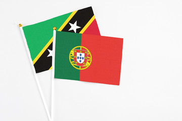 Portugal and Saint Kitts And Nevis stick flags on white background. High quality fabric, miniature national flag. Peaceful global concept.White floor for copy space.