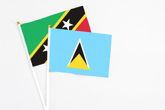 Saint Lucia and Saint Kitts And Nevis stick flags on white background. High quality fabric, miniature national flag. Peaceful global concept.White floor for copy space.