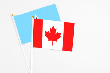 Canada and Saint Lucia stick flags on white background. High quality fabric, miniature national flag. Peaceful global concept.White floor for copy space.