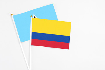 Colombia and Saint Lucia stick flags on white background. High quality fabric, miniature national flag. Peaceful global concept.White floor for copy space.